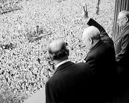 Ernest Bevin standing to the right of Winston Churchill who waves to crowds on VE Day, Whitehall, London, England, 8th of May 1945